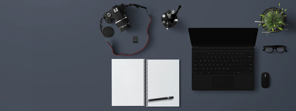 scrivania con notebook ,fotocamera e quaderno