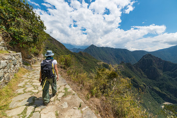 Fototapeta na wymiar Backpacker exploring the steep Inca's footpaths of Machu Picchu, the most visited travel destination in Peru. Summer adventures in South America.