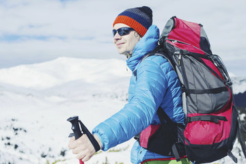 Fototapeta na wymiar Hiker in winter mountains. Man with backpack trekking in mountains. Winter hiking.