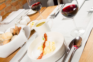 Cream of sorrel and green vegetables soup with quail egg, sour cream, mashed potatoes and crispy bacon served in a jug in a restaurant