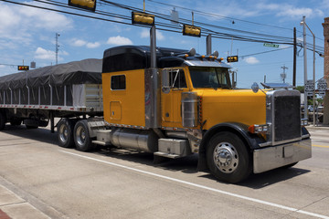 Yellow truck in a highway crossing a small american town  Concept for transportation and transportation background © Tiago Fernandez