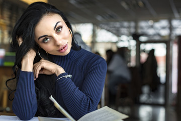 young woman reading a book in a cafe