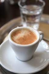 Espresso in weißer Porzellantasse mit einem Glas Wasser