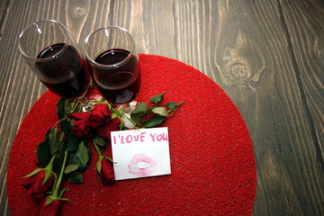 Wine in glasses, red roses and I love you text message on wooden background, valentine`s day concept