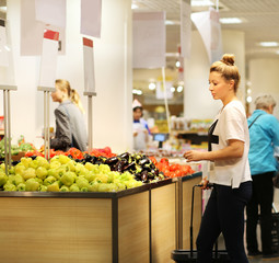 Woman shopping in supermarket reading product information. Checking list.Woman   choosing  a dairy products at supermarket 