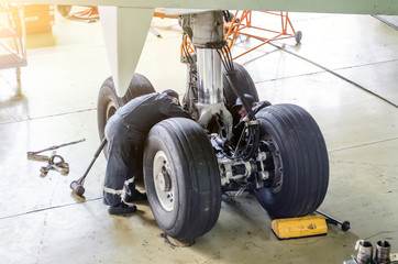 Repair of the chassis landing gear of the aircraft, two technicians of mechanics at work in the...