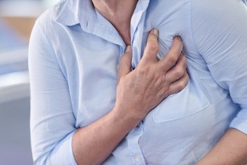 Woman clutching her chest, cropped view