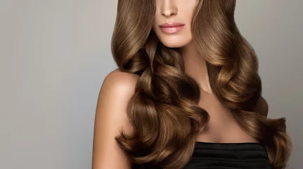 Photo sur Plexiglas Salon de coiffure Belle fille modèle avec de longs cheveux ondulés et brillants. Femme brune avec une coiffure frisée