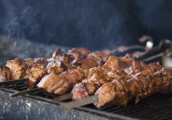 The fried shish kebab cooking on a metal close up of a spit. Fried meat is made in a barbecue. Fried on charcoal. Street food.