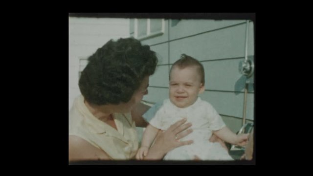 1959 Mother holding infant son in suburban backyard 1959