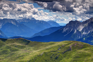 Glowing blue mist above Piave river valley between Dolomiti Friulane Prealpi Carniche and Dolomiti di Sesto ridges with white gray cumulus clouds from sunny Carnic Alps, Belluno Veneto Italy Europe