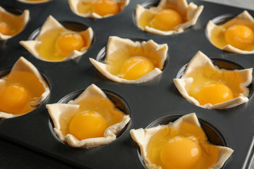 Baking mold with raw eggs in dough, closeup