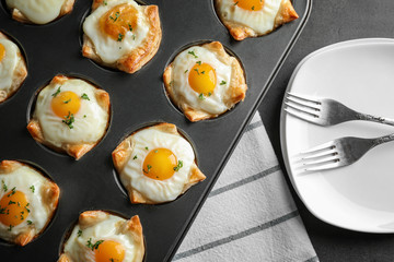 Baking mold with tasty eggs in dough on table