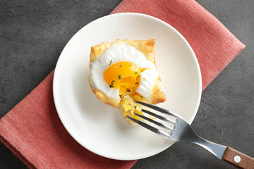 Tasty baked egg in dough with fork on plate
