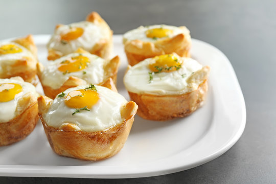 Tasty baked eggs in dough on plate, closeup
