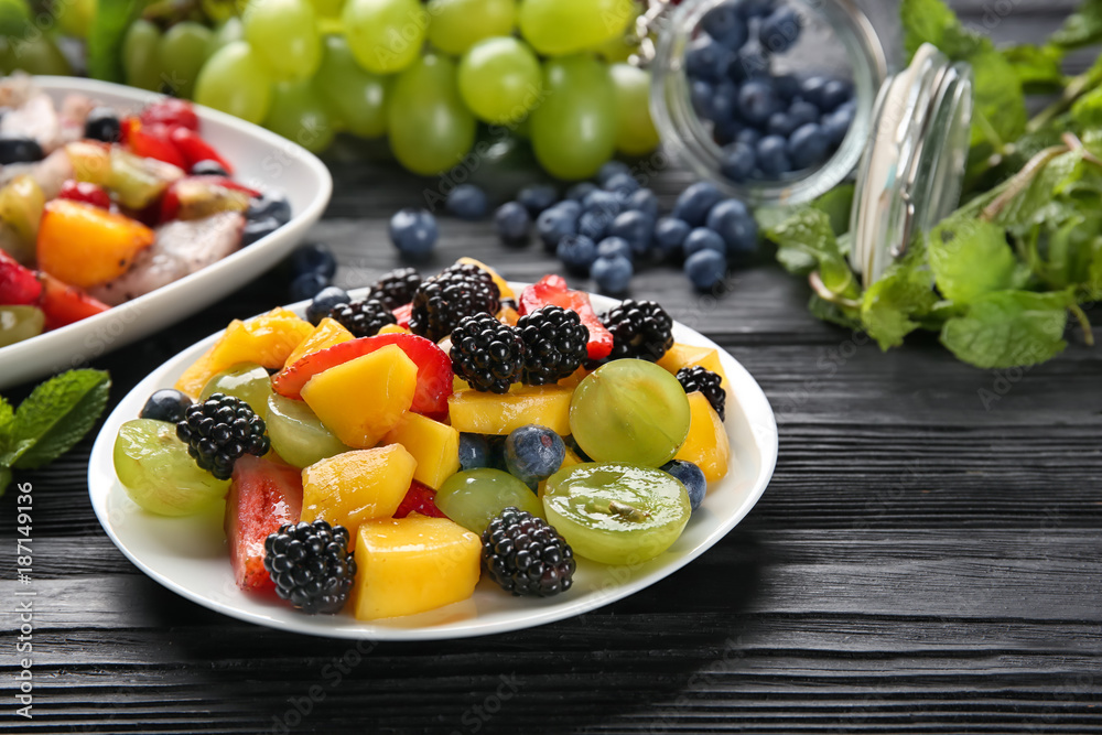 Wall mural plates with delicious fruit salad on wooden table