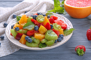 Plate with delicious fruit salad on wooden table
