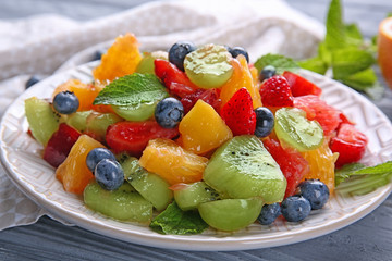 Plate with delicious fruit salad on table