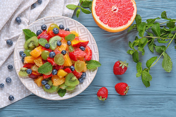 Plate with delicious fruit salad on wooden table