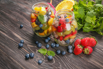 Jars with delicious fruit salad on wooden table