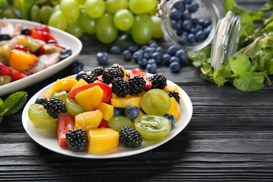 Plates with delicious fruit salad on wooden table
