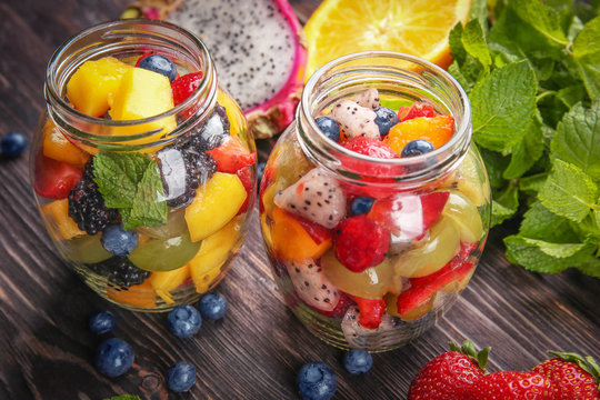 Jars with delicious fruit salad on wooden table