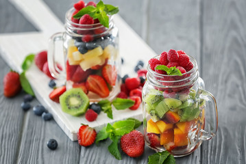 Mason jars with fruits and berries on table