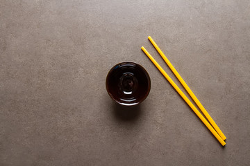 Chinese food. Two chopsticks for eating. Food sticks. A bowl. Dark background.