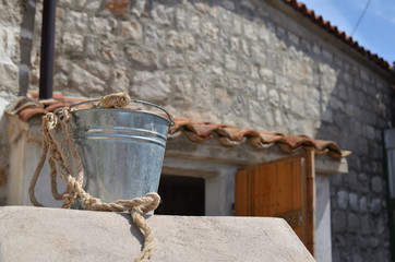 Fototapeta na wymiar Silver tin pail in front of an old Mediterranean house