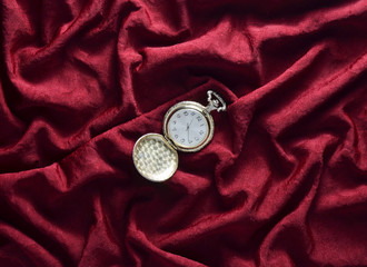 Vintage gold pocket watch on a red silk background. Top view.