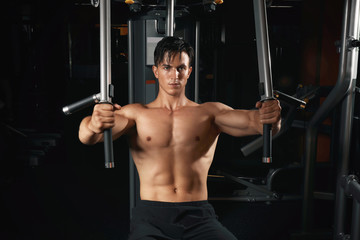 Fototapeta na wymiar Young man training on exercise machine in gym