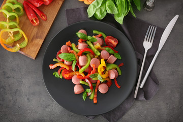 Plate with vegetable salad and sausage on kitchen table