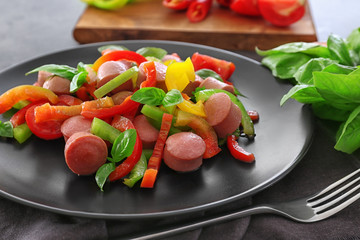 Plate with vegetable salad and sausage on kitchen table