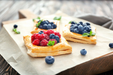 Tasty pastries with berries on board, closeup