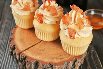 Tasty cupcakes with bacon on stump