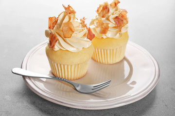 Tasty cupcakes with bacon on plate