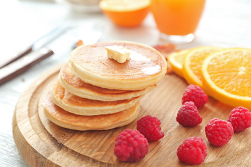 Tasty breakfast with pancakes and fruits on wooden board