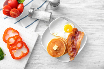 Tasty breakfast with pancakes, bacon and fried egg on table