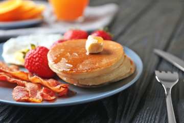 Tasty breakfast with pancakes, bacon and fried egg on table