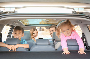 Young couple with their little children in car