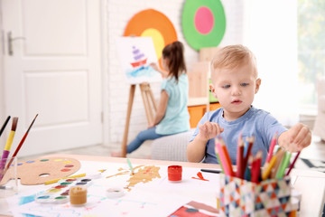 Fototapeta premium Little boy and blurred girl painting indoors