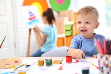 Obraz premium Little boy and blurred girl painting indoors