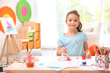 Little girl painting at table indoors