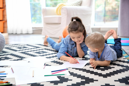 Little girl and boy drawing on floor at home