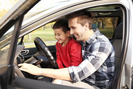 Young father with little son in driver seat of car