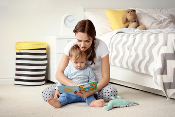 Beautiful young woman reading to her baby at home