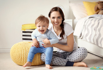 Fototapeta premium Beautiful young woman with her baby at home