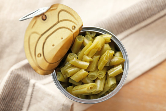 Open tin can of green beans on table, closeup