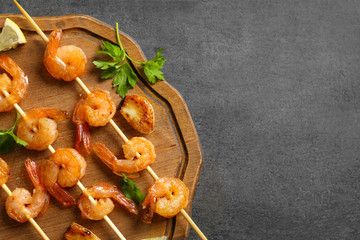Delicious fried shrimps with garlic on wooden board, top view