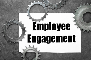 Sheet of paper with text EMPLOYEE ENGAGEMENT and tooth wheels on table © Africa Studio